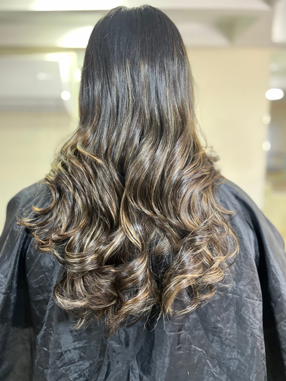 Long wavy hair with lighter highlights shown from the back