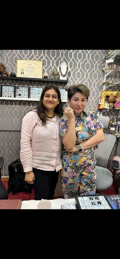 Two people posing inside Shree Astrology with shelves and framed certificates in Andheri West