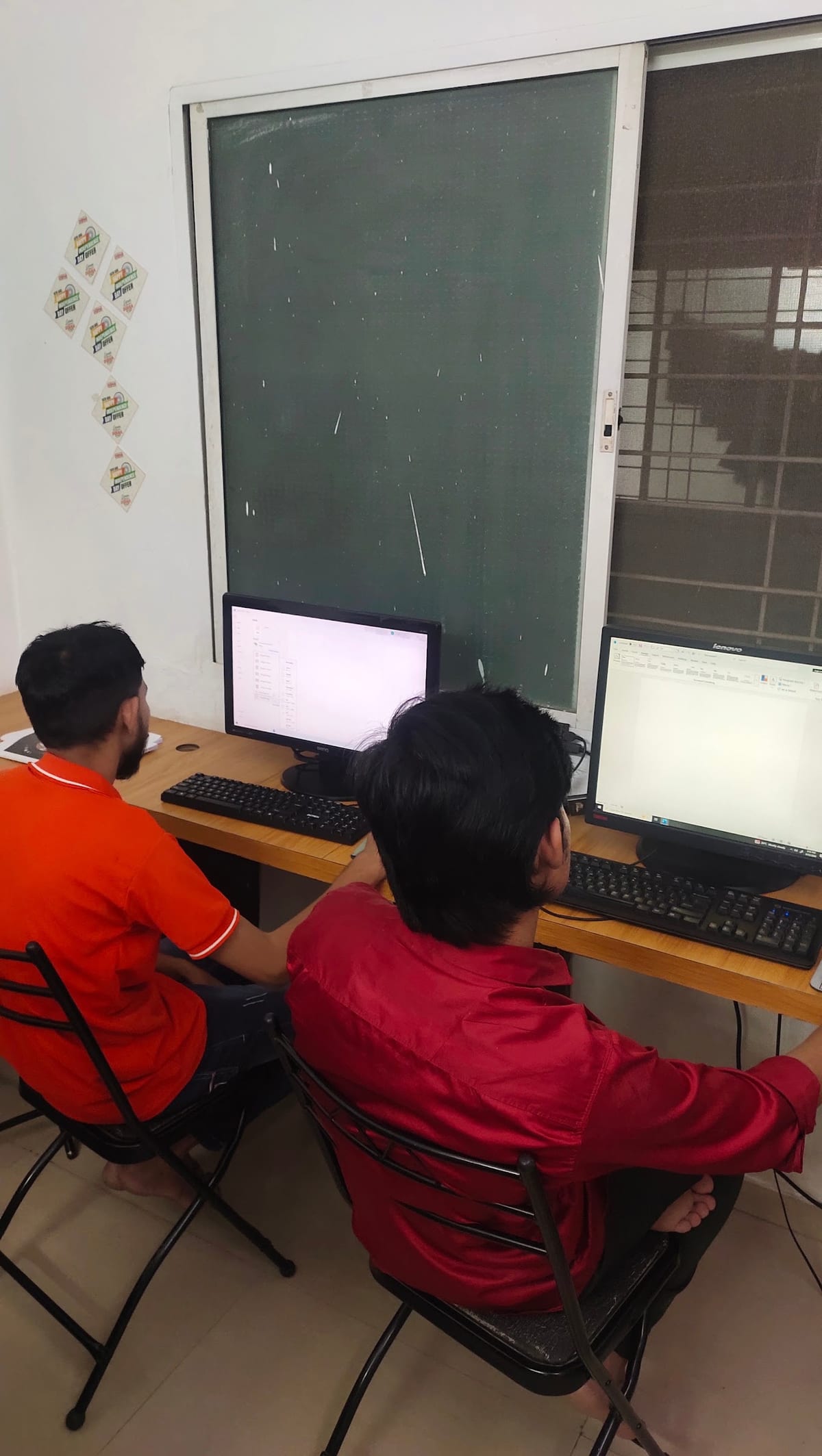 Two learners working at desktop computers in a training room