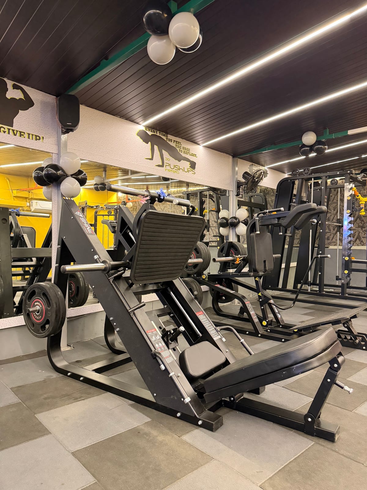 Strength-training and cardio machines, mirrors, and ceiling lights in gym interior