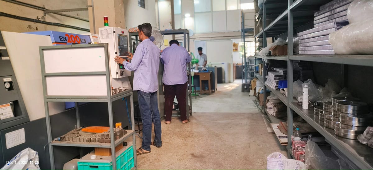 Workers operating equipment in a workshop aisle lined with storage shelves