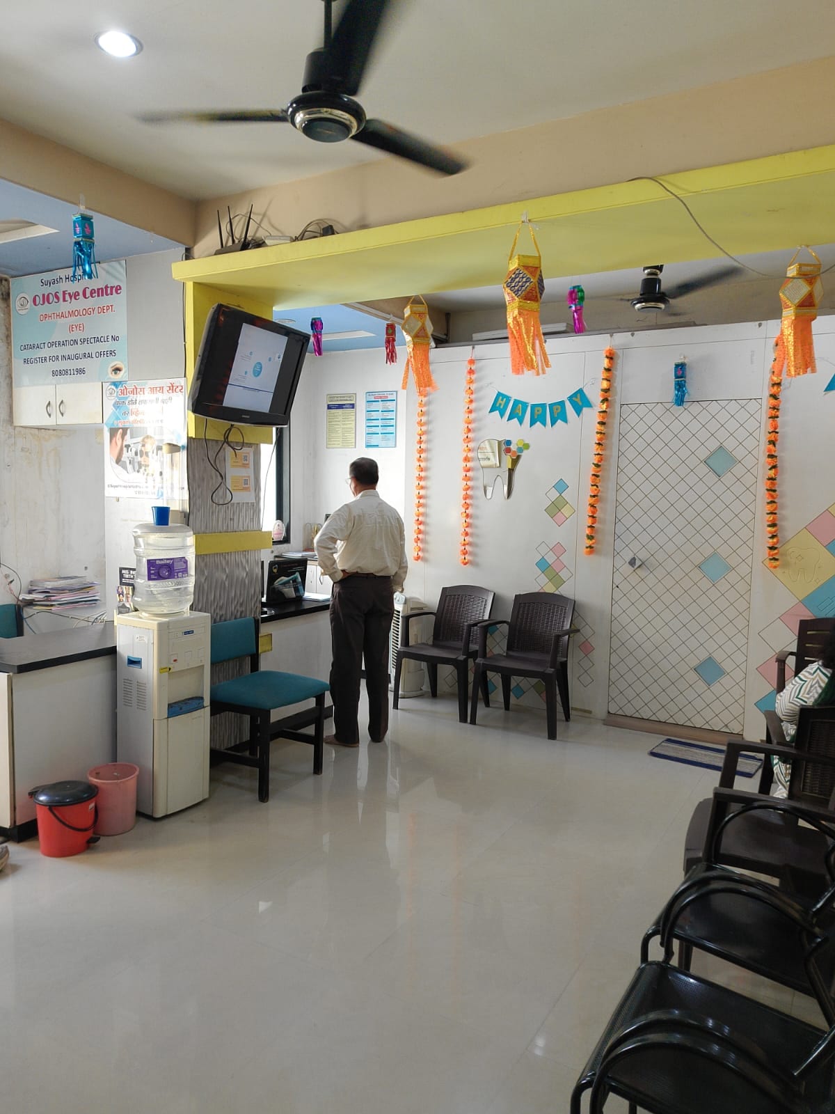 Clinic waiting area with chairs, reception desk, water dispenser and wall decorations