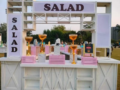 Decorated outdoor salad stand with pink shelving and gold glasses of drinks