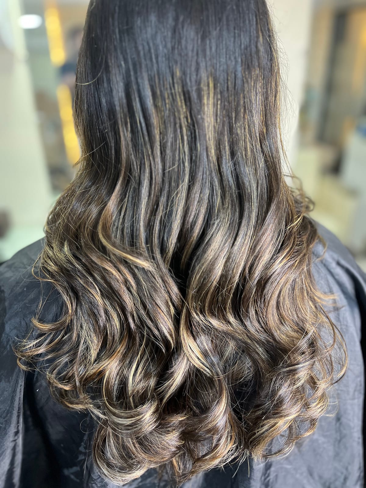 Long wavy hair with highlighted curls seen from the back