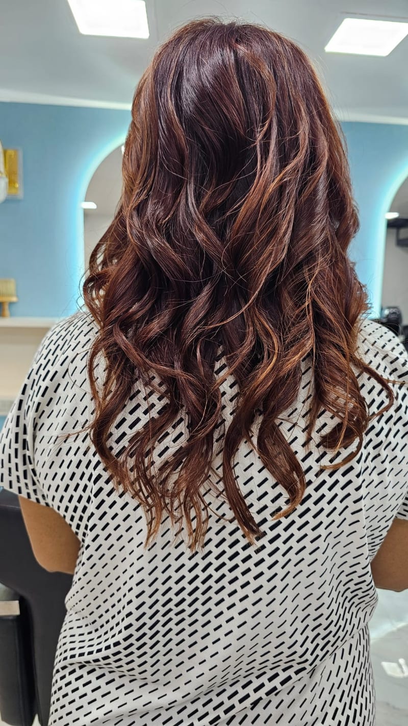 Client with long wavy brown hair seated in a salon chair