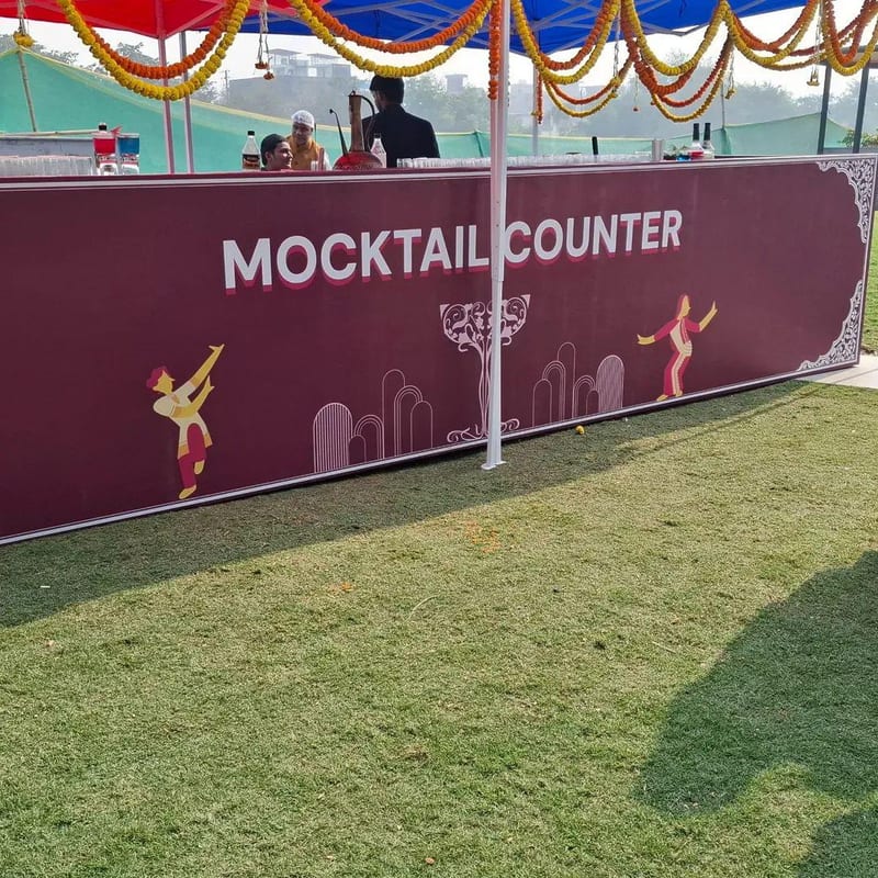 Mocktail counter beneath a decorated canopy on a grass lawn
