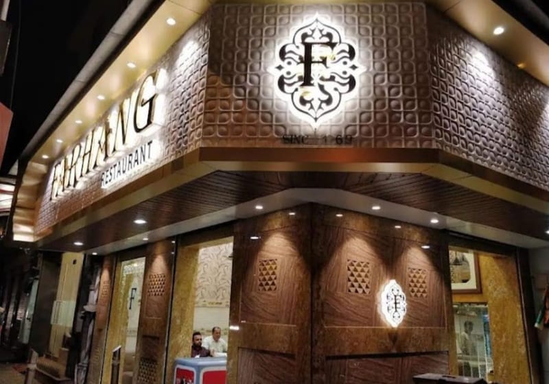 Illuminated Farhang Restaurant storefront with patterned facade and wooden entrance doors in Fort