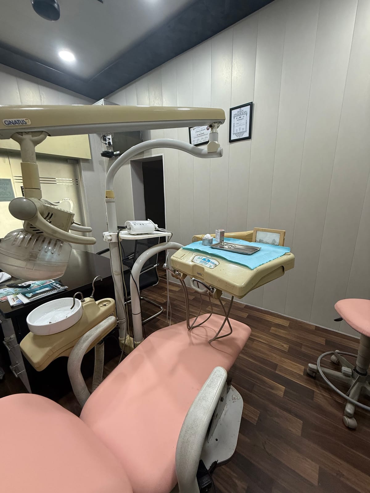 Dental treatment room with a pink examination chair, overhead lamp and instrument tray at Shravit clinic in Varanasi