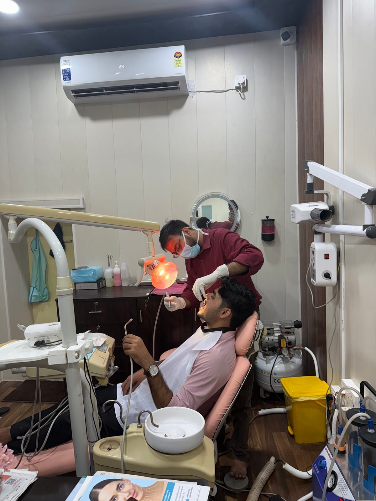 Dental professional examining a seated patient in a treatment room