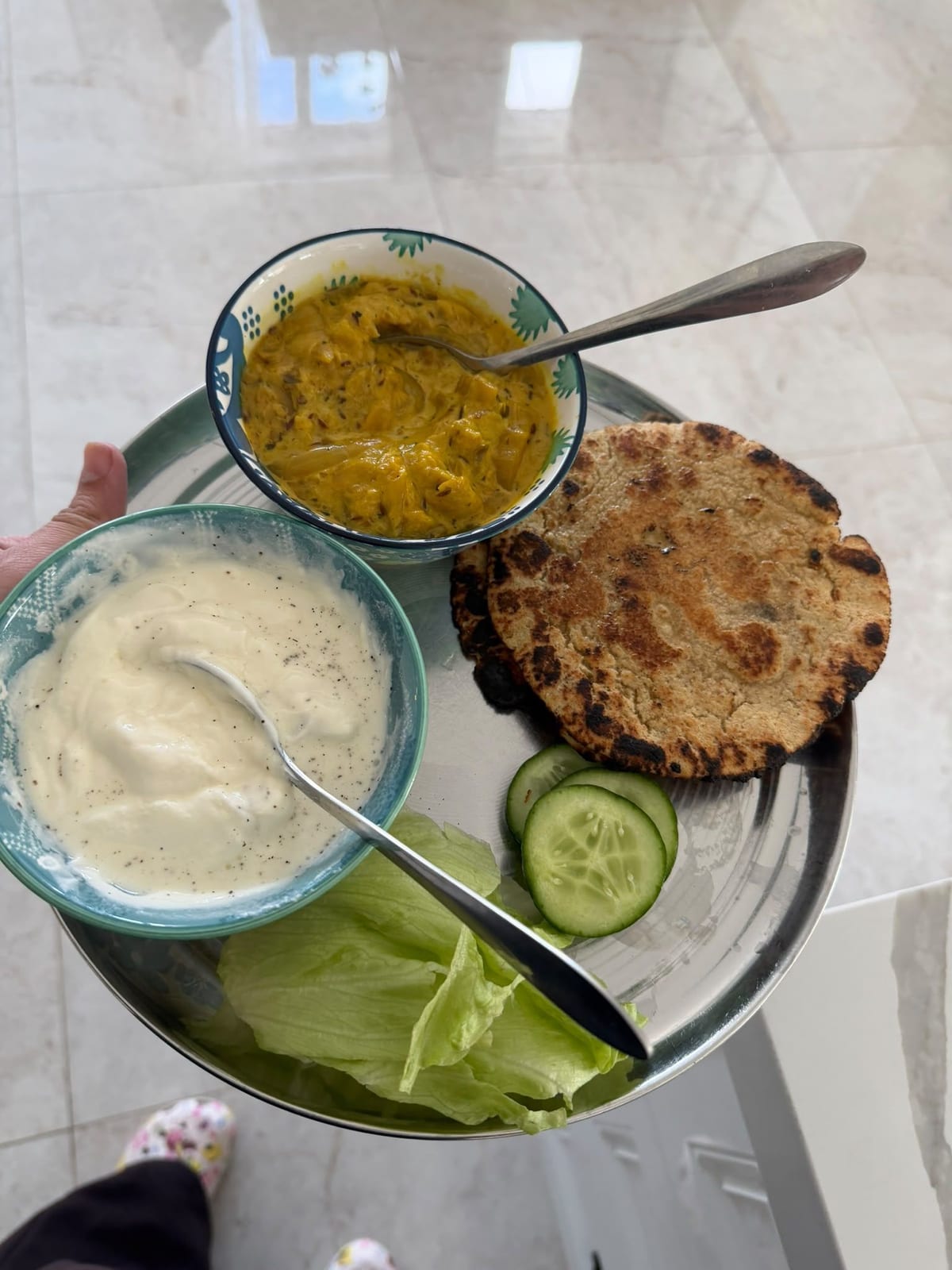 Plate of flatbread with two bowls of sauce, cucumber slices and lettuce