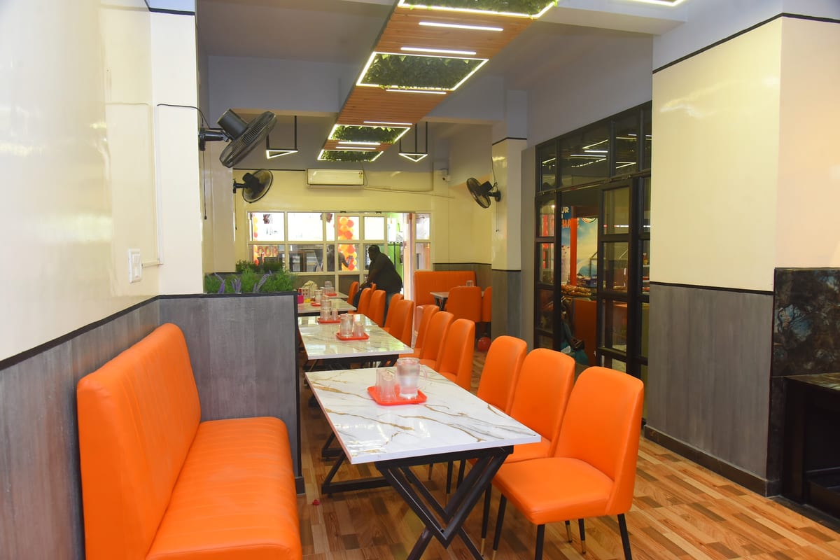 Interior dining area with orange booth seating, tables, wall fans and ceiling lights