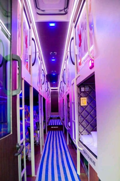 Illuminated sleeper corridor with enclosed berths and a blue striped floor