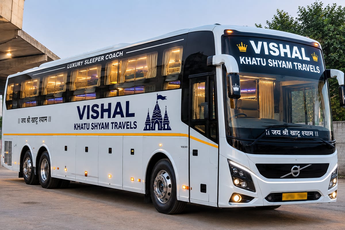 White luxury sleeper coach marked Vishal Khatu Shyam Travels parked under a structure