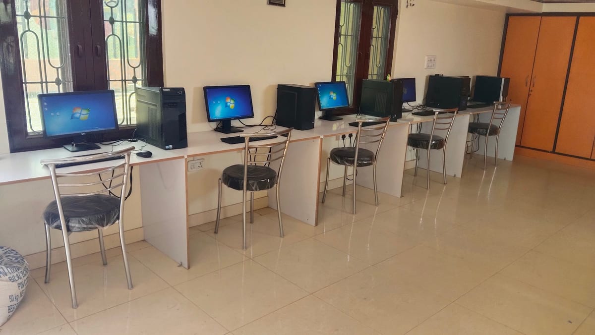 Computer workstations with monitors and chairs inside the tiled lab