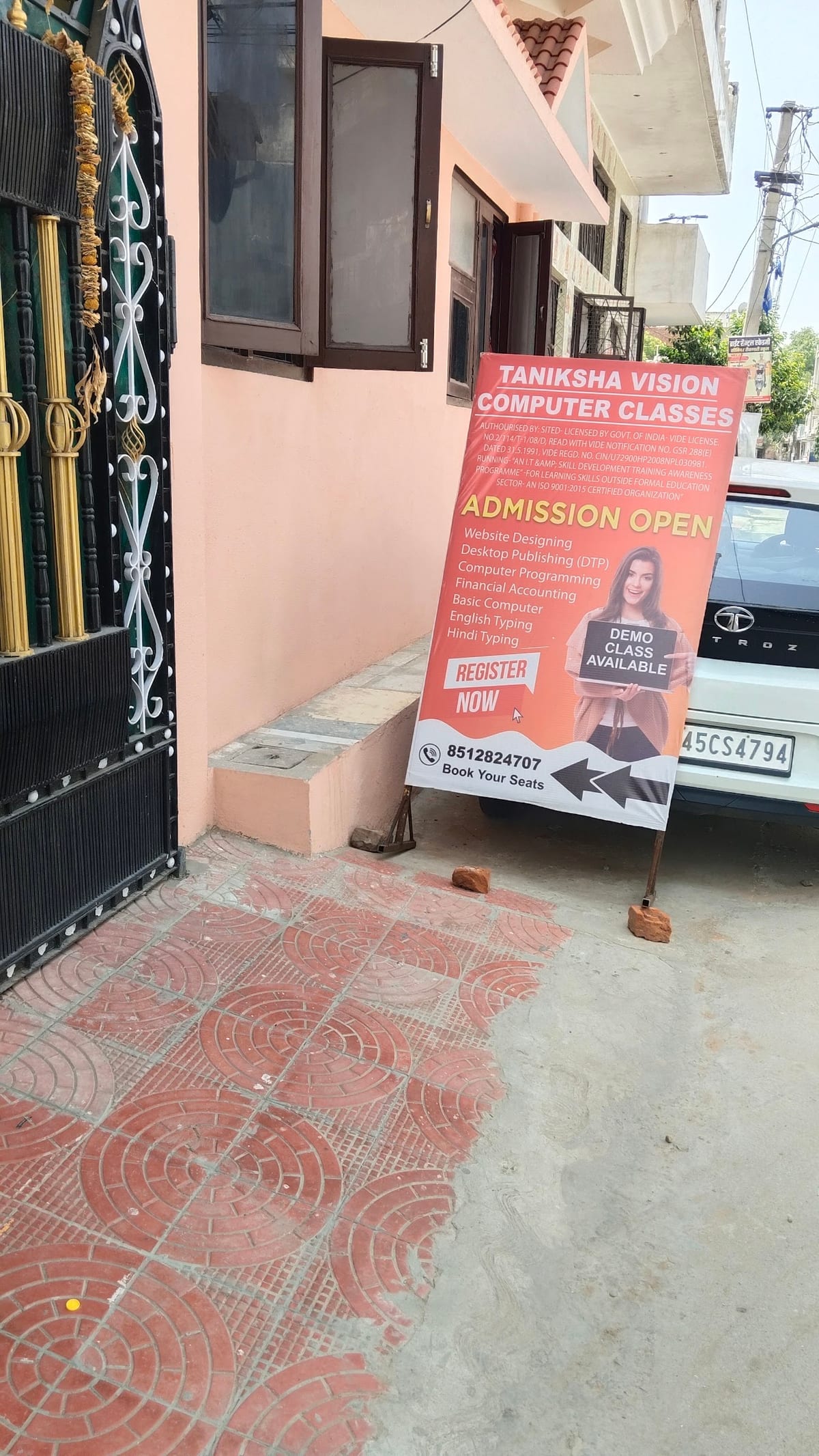 Building entrance beside a standing computer classes admission sign