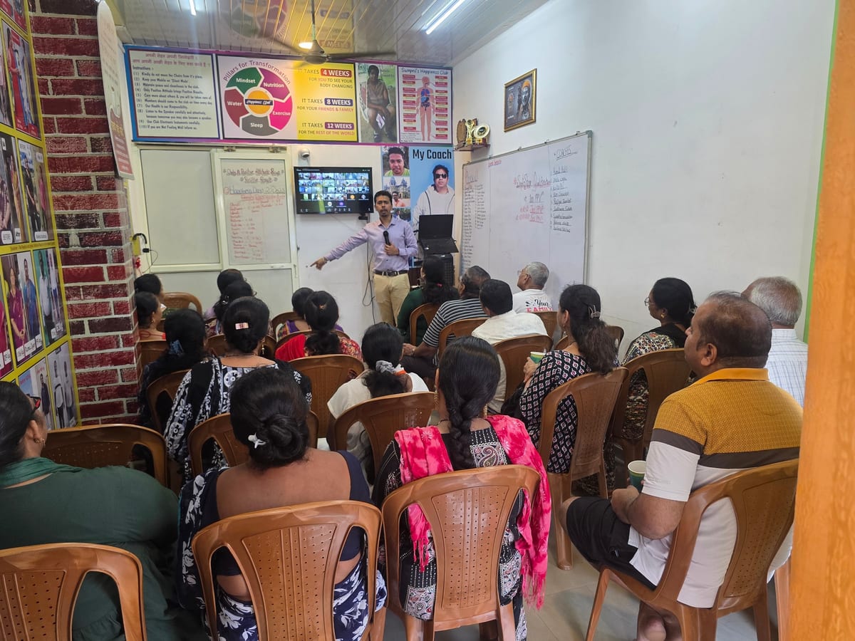 Seated group facing a presenter in a room with wall posters and a whiteboard