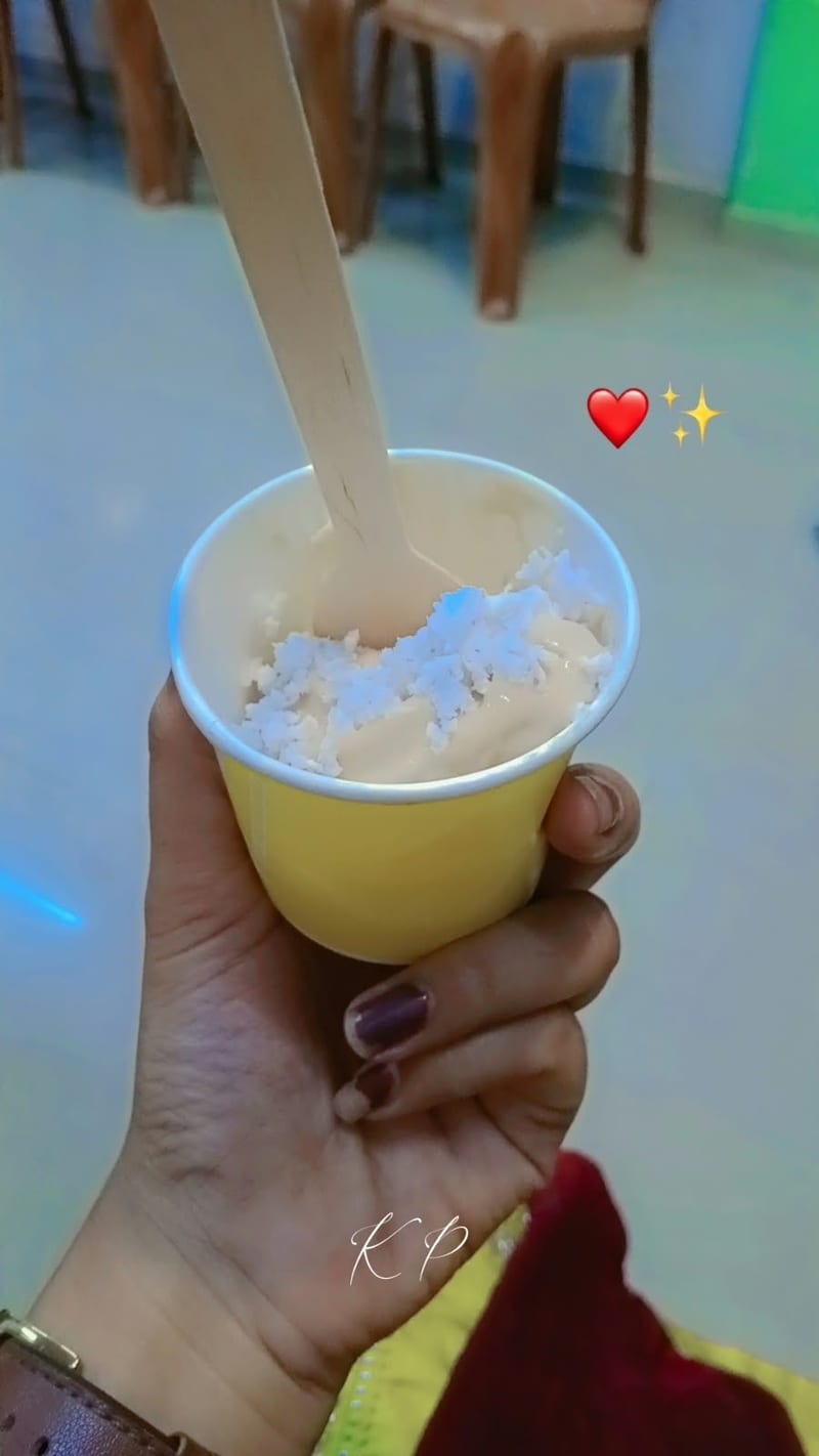 Hand holding a yellow cup of pale frozen nutrition dessert with a spoon