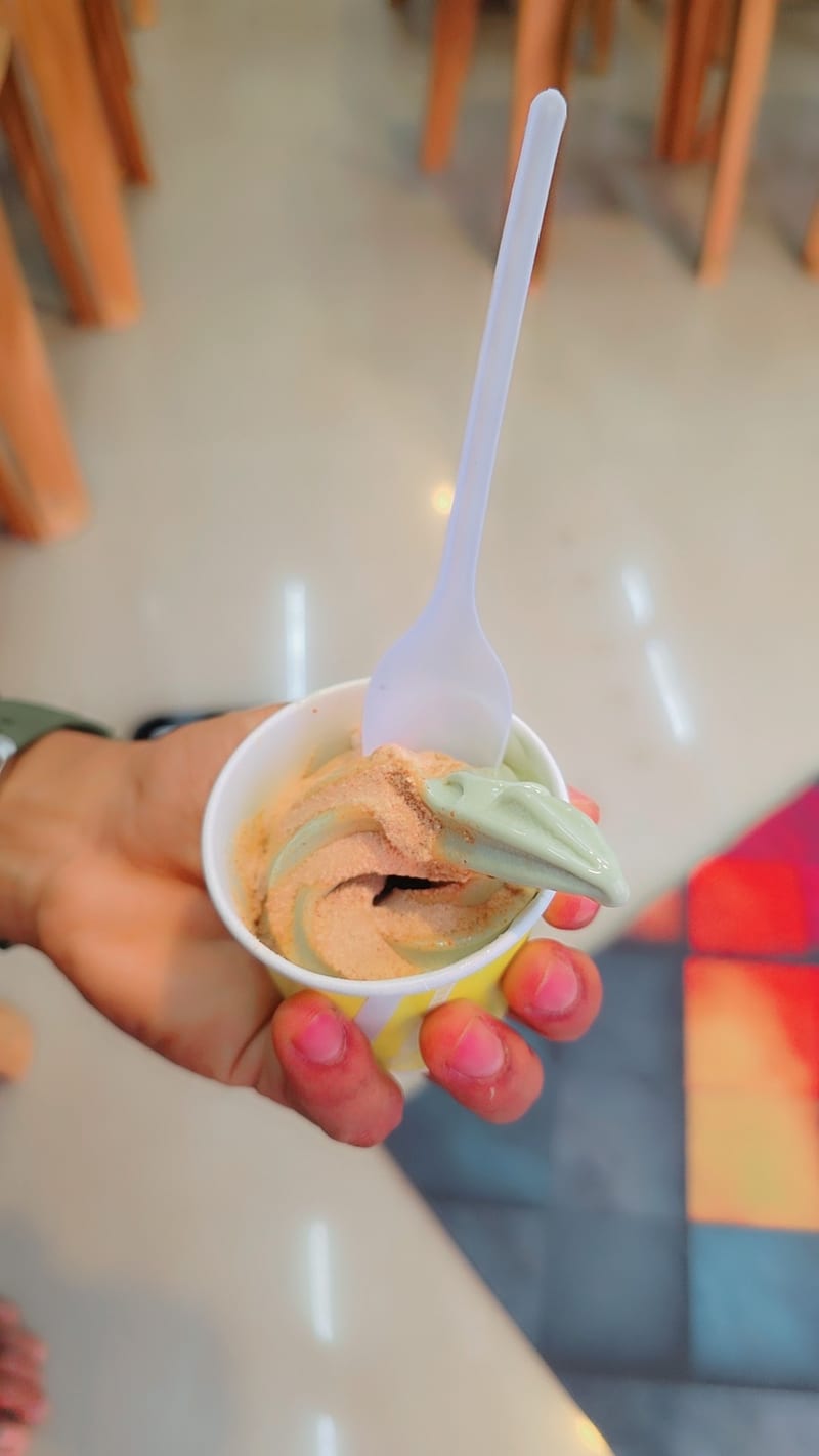 Hand holding a cup of swirled healthy dessert with a spoon at Happiness Club