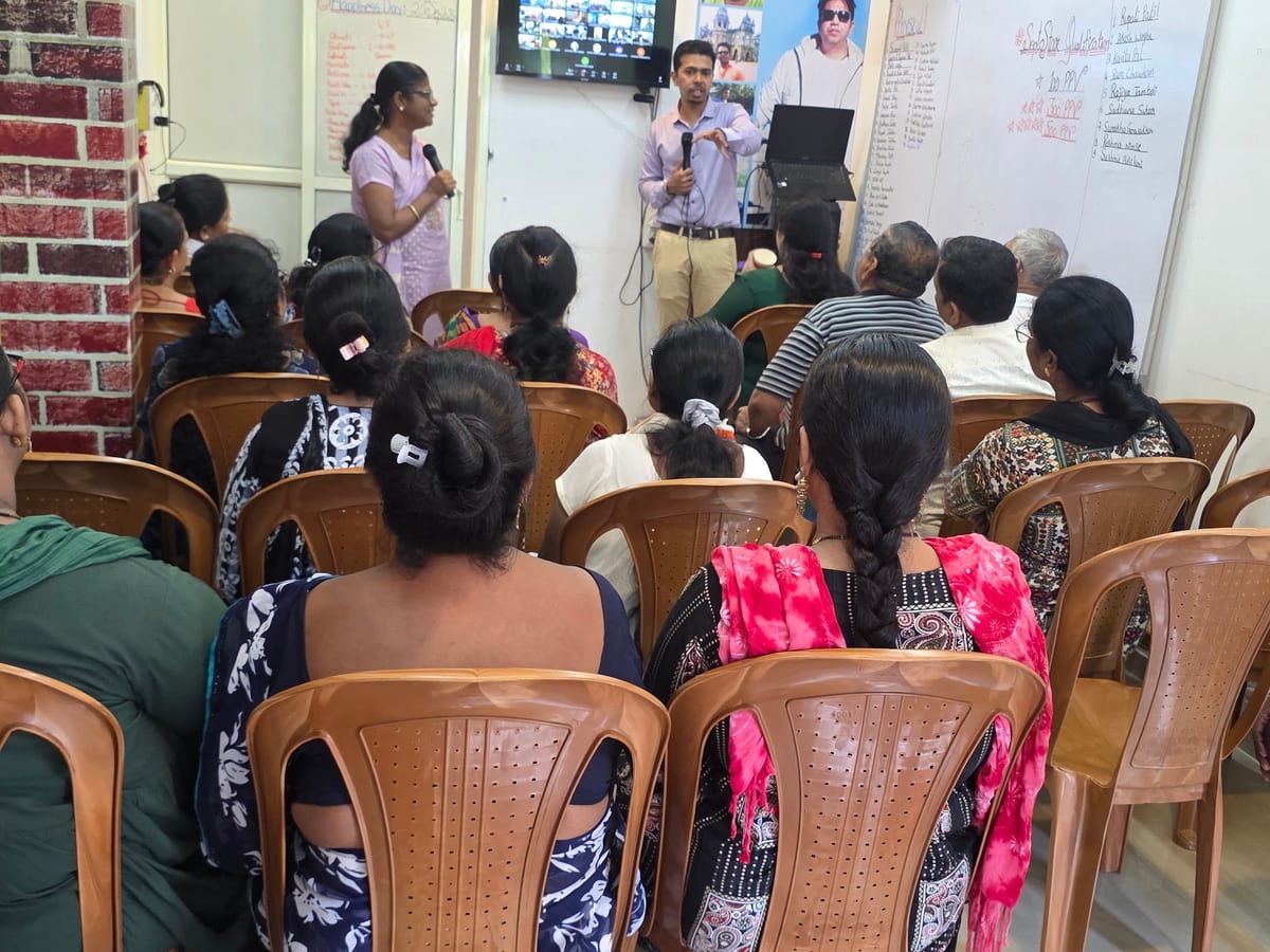 Seated audience listening to two presenters at the front of a room