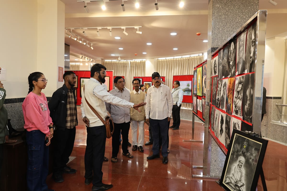 Visitors viewing framed artwork on partition walls in an indoor gallery