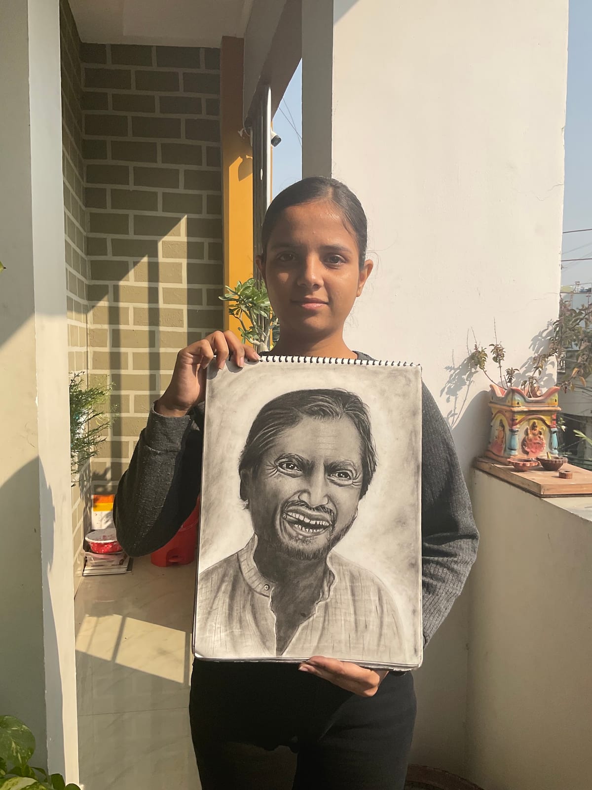 Person holding a pencil portrait drawing on paper