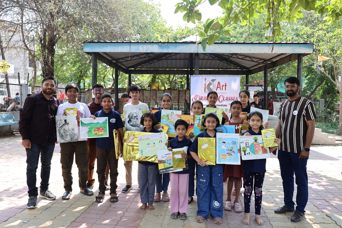 Adults and children holding colourful artwork together outdoors