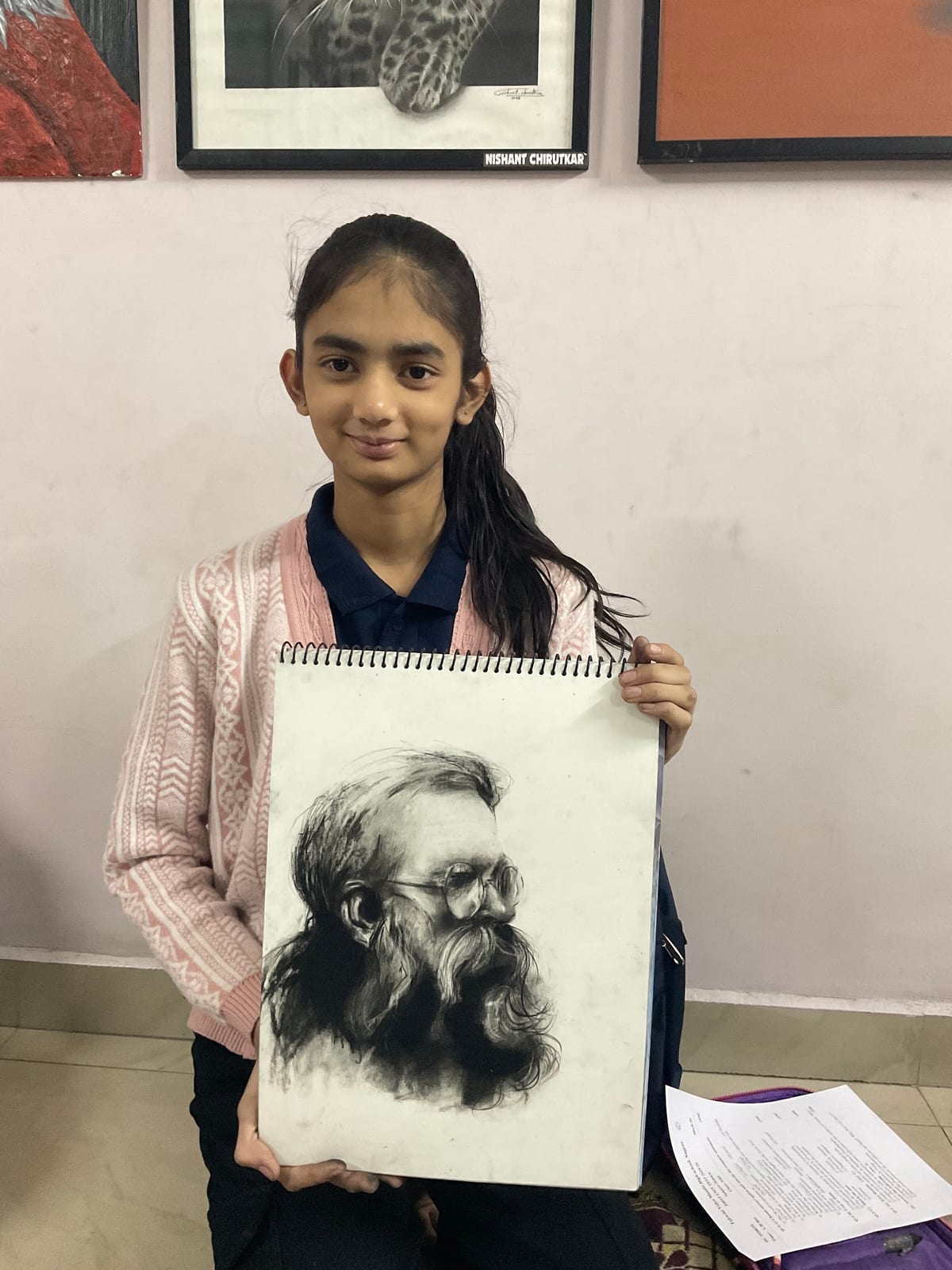 Girl holding a sketchbook with a detailed black-and-white portrait of a bearded man